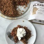 Plate of apple crumble next to the rest of the apple crumble dish and a bag of Manitoba Milling Flaxseed