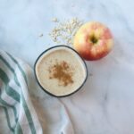 Apple pie smoothie in a cup next to a whole apple